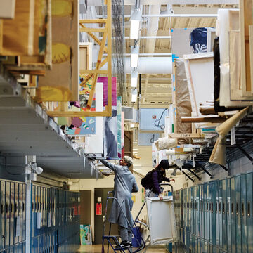 A hallway lined with lockers and large canvases.